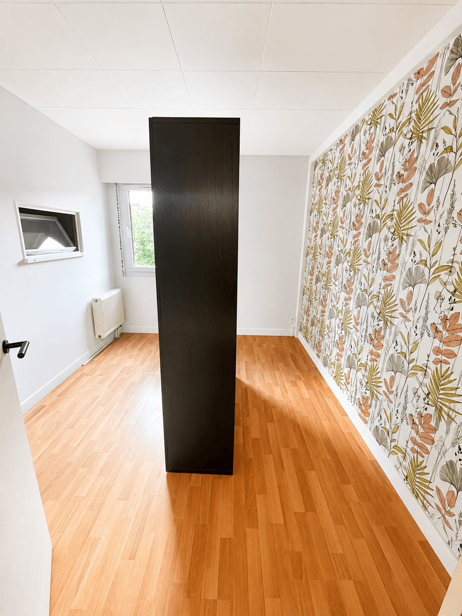 Papier peint à motif floral posé sur un mur de chambre, murs voisins peints en blanc