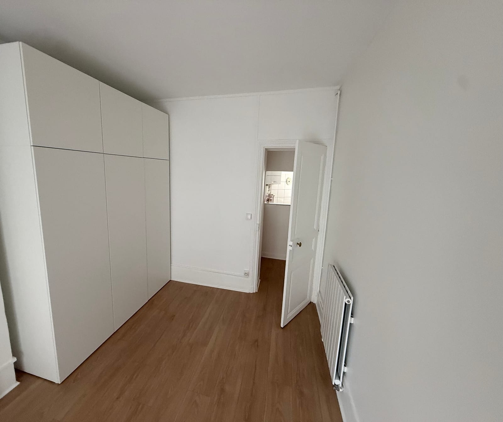 Chambre repeinte en blanc à Paris 17e : murs, plafond, plinthes et porte à moulures
