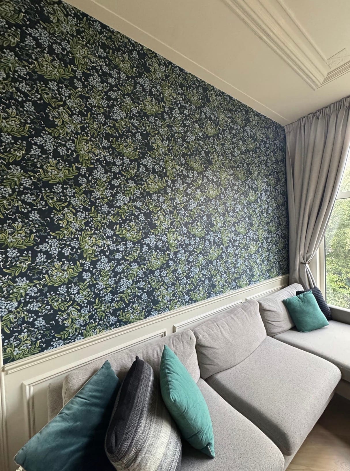 Mur de séjour habillé d'un papier peint fleuri sombre dans un appartement à Bois-Colombes