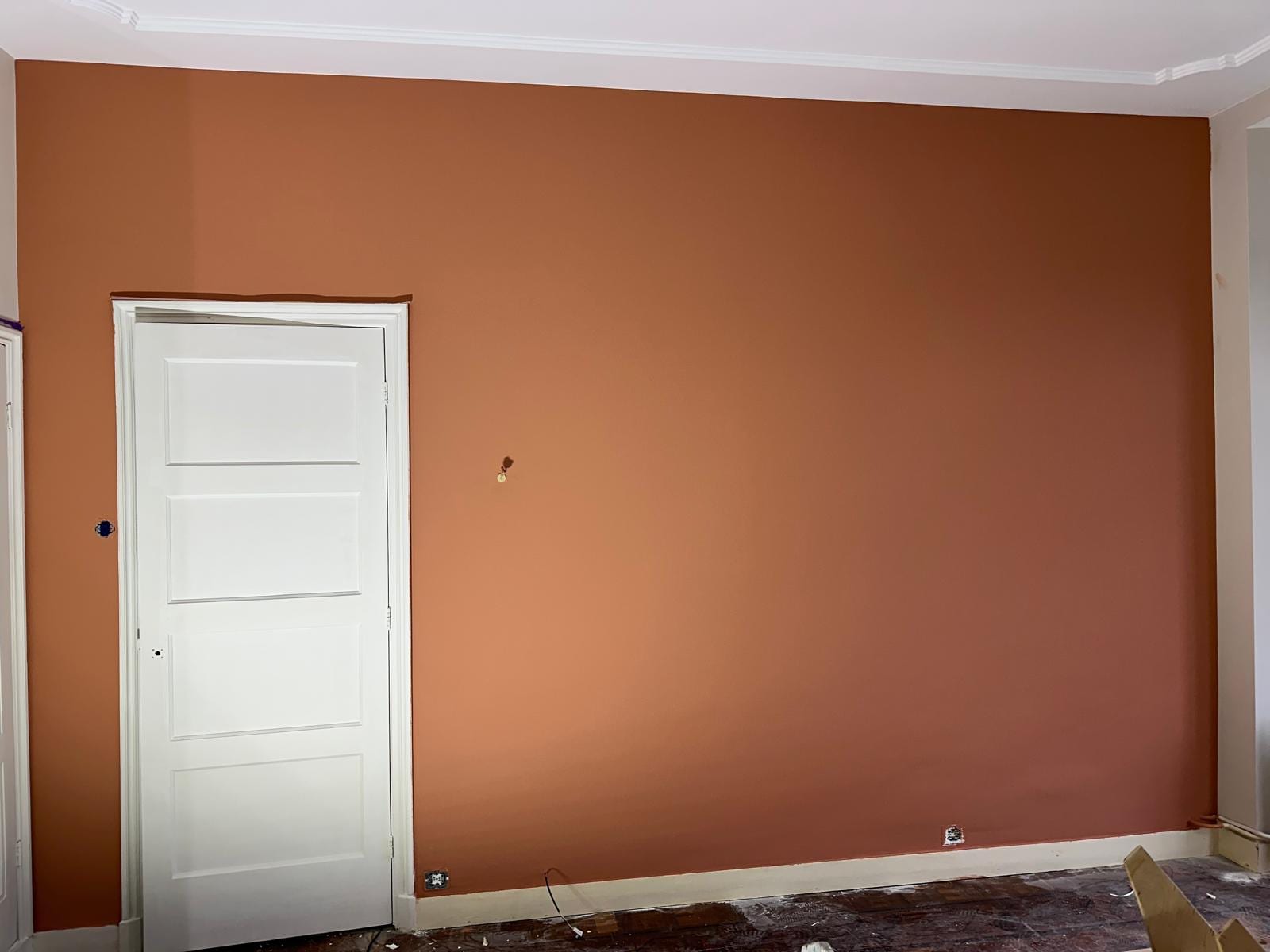 Mur de séjour peint en terracotta dans un T3 à Colombes, porte blanche à panneaux