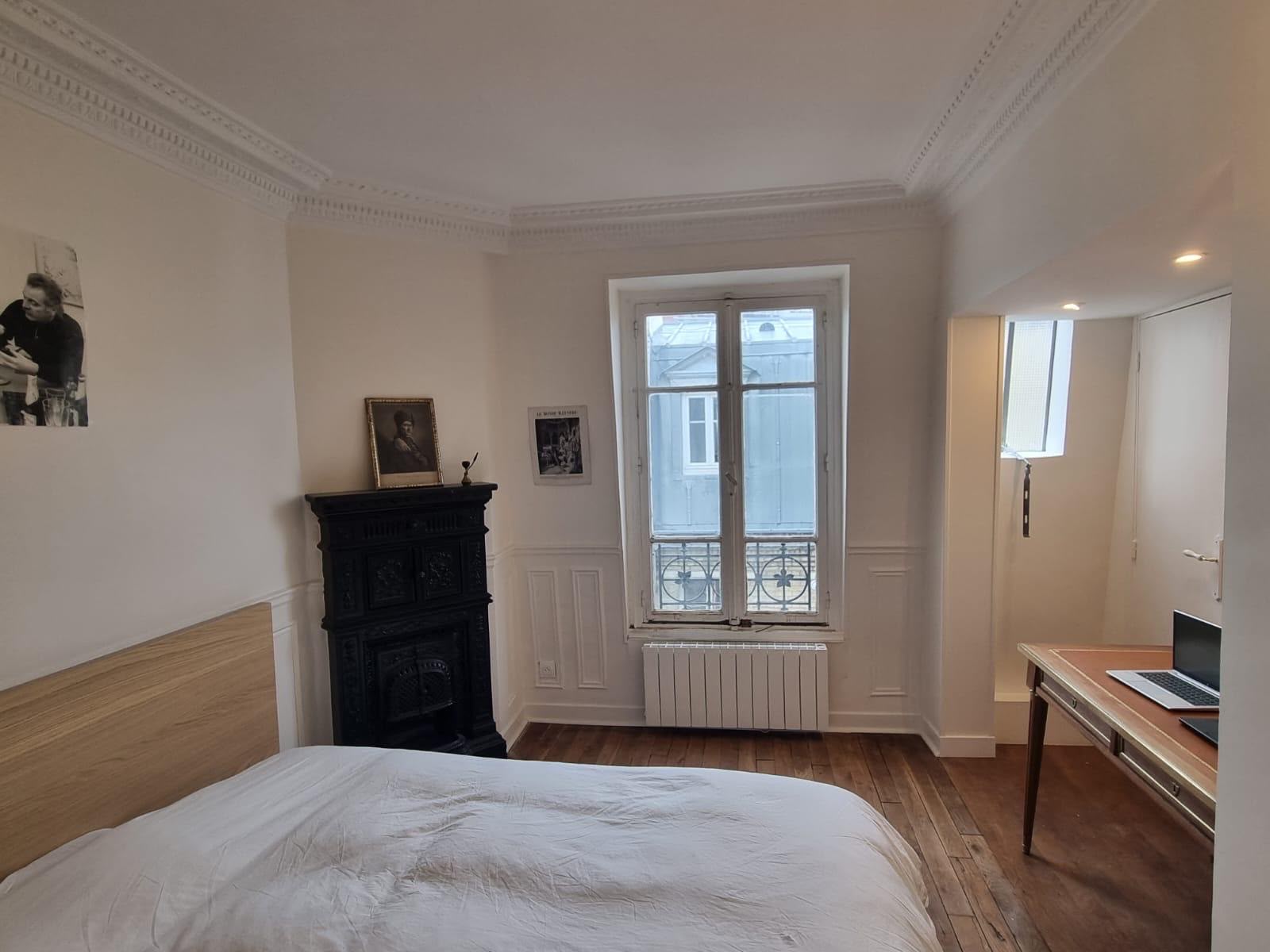 Chambre de maison ancienne repeinte en blanc, corniche moulurée et poêle en fonte conservé