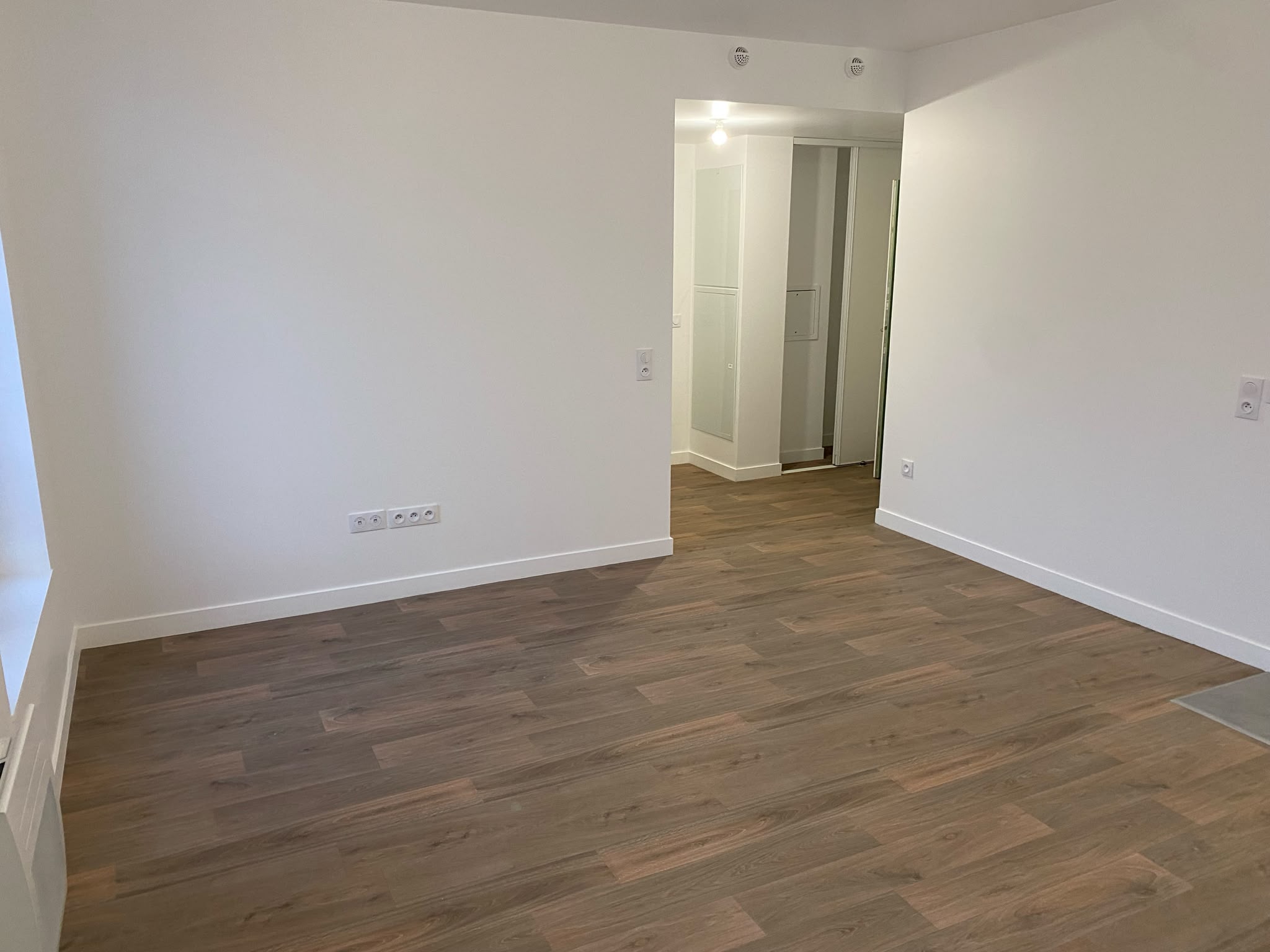 Studio livré après rénovation complète, murs blancs et sol stratifié chêne clair