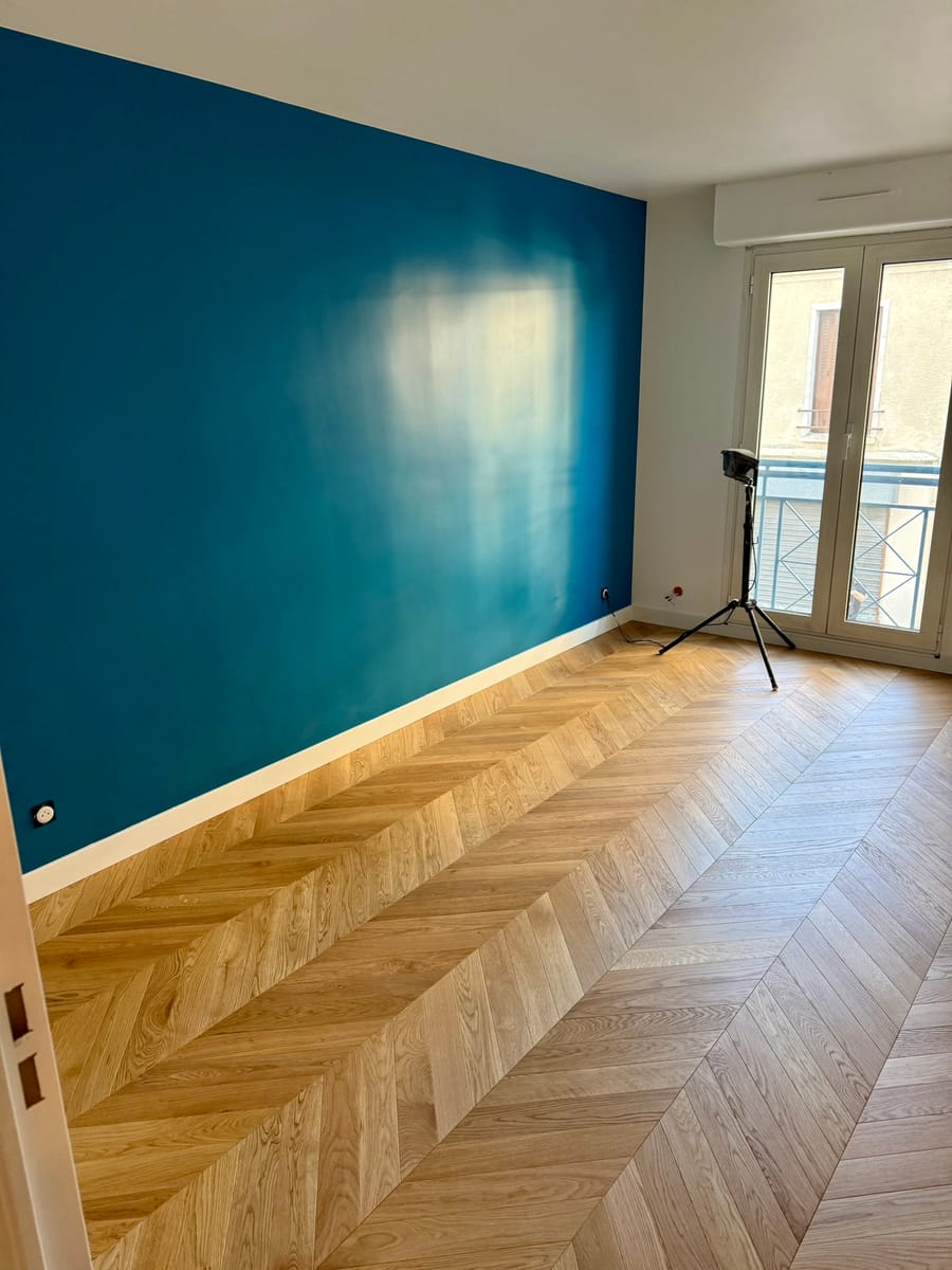 Mur d'accent bleu canard et parquet à chevrons dans un séjour rénové