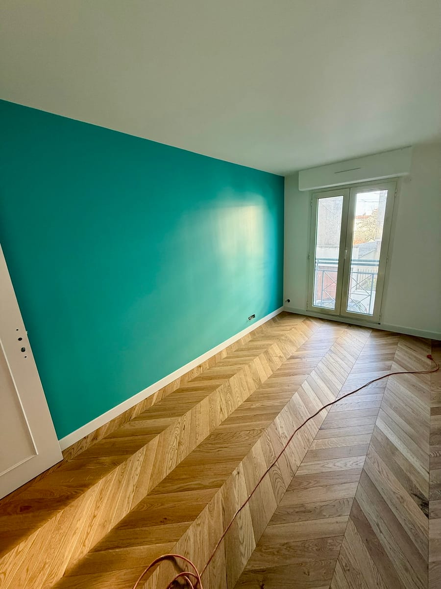Mur d'accent bleu canard dans une pièce à parquet chevrons